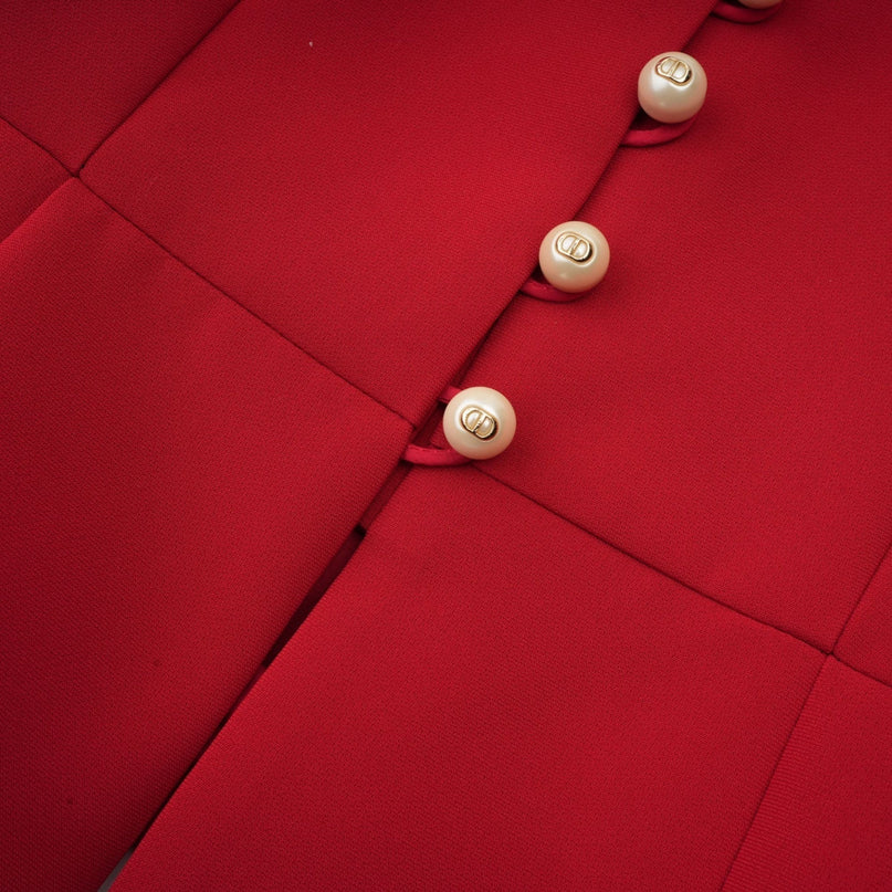 Woman wearing red pleated blouse and matching skirt set Colette style outfit standing against plain background