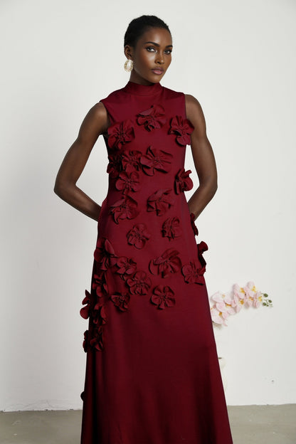 Woman wearing red sleeveless maxi dress with bow tie and faux flower embellishments