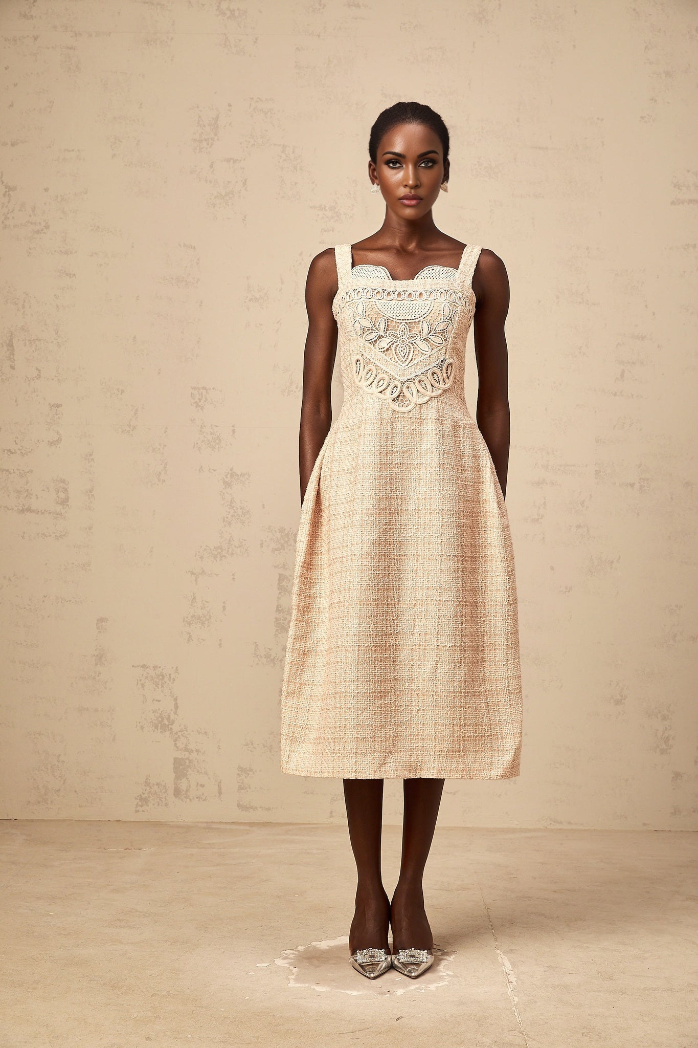 Woman wearing short beige dress with intricate embroidery and woven pattern throughout