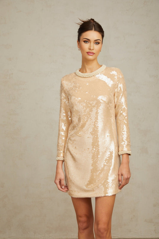 Woman wearing short beige dress with pearl and sequin embellishments