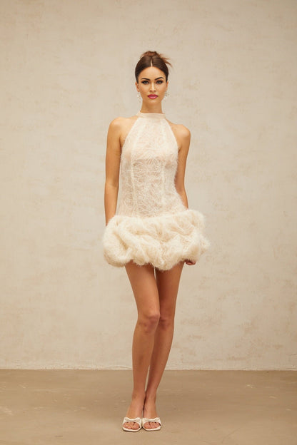 Woman wearing short beige textured mini dress with puff sleeves and gathered fabric detail