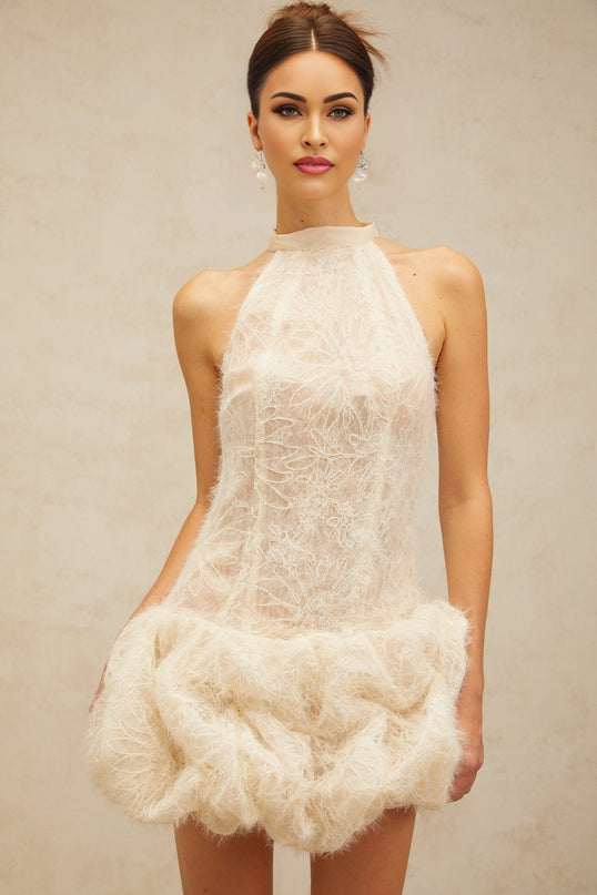 Woman wearing short beige textured mini dress with puffed sleeves and round neckline standing against neutral background