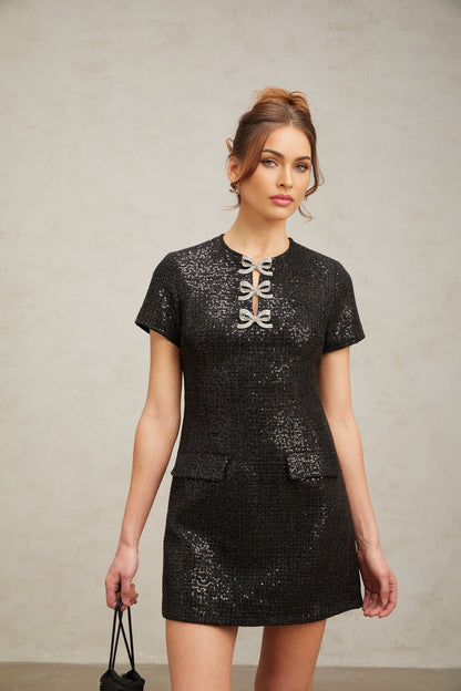 Woman wearing short black dress with glitter details and sleeveless design