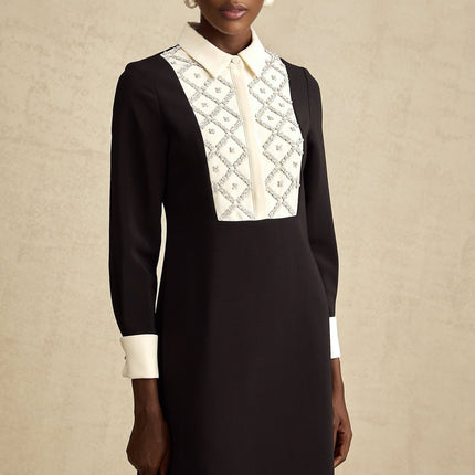 Woman wearing short black dress with white collar and cuffs embellished with crystals