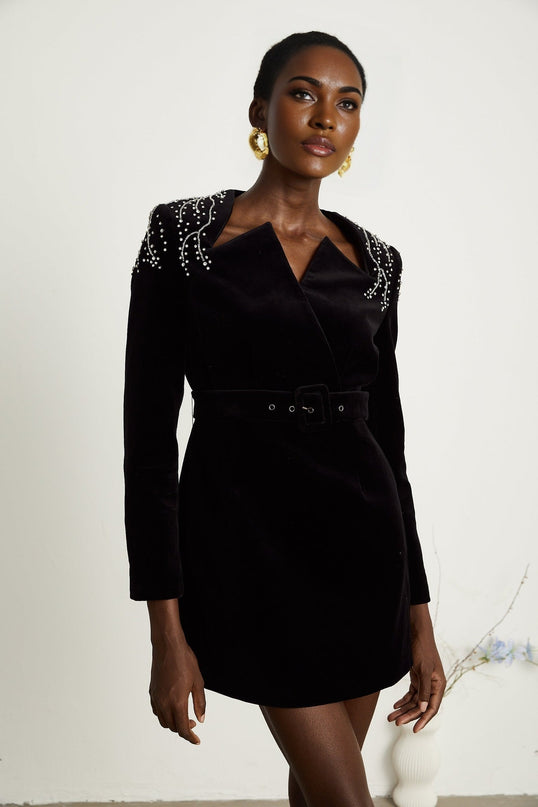 Woman wearing short black velvet dress with crystal embellishments and fitted silhouette