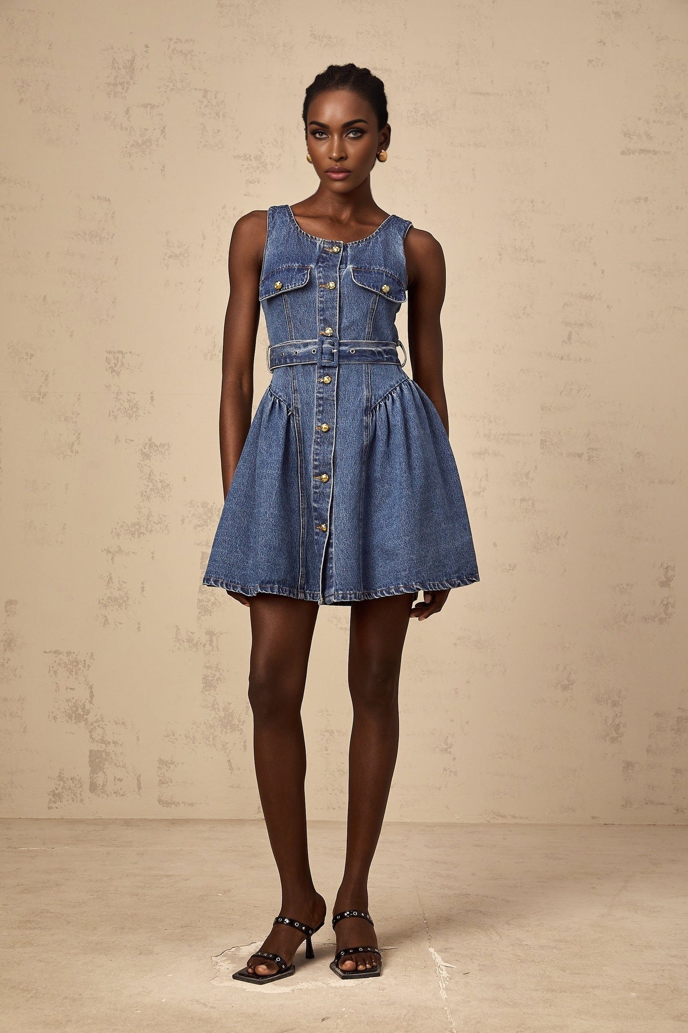 Woman wearing short blue denim dress with belt at waist