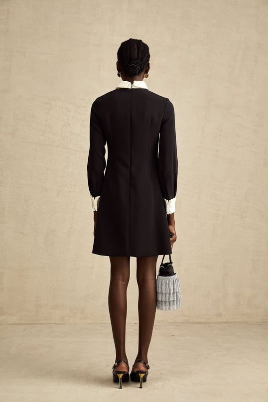Woman wearing short blue mini dress with contrasting pink floral embellishments and spaghetti straps