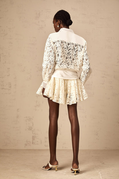 Woman wearing short off white lace dress with floral pattern and shirt collar