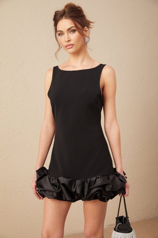 Woman wearing short pink dress with ruffled details and open back design