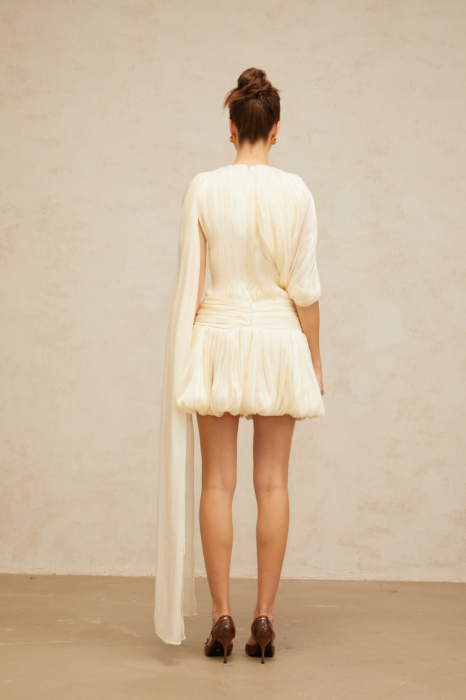 Woman wearing short pleated dress with ribbon accent at waist flared skirt and sleeveless design