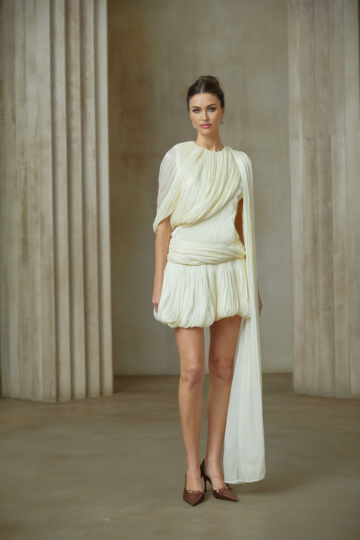 Woman wearing short pleated white dress with ribbon accent at waist