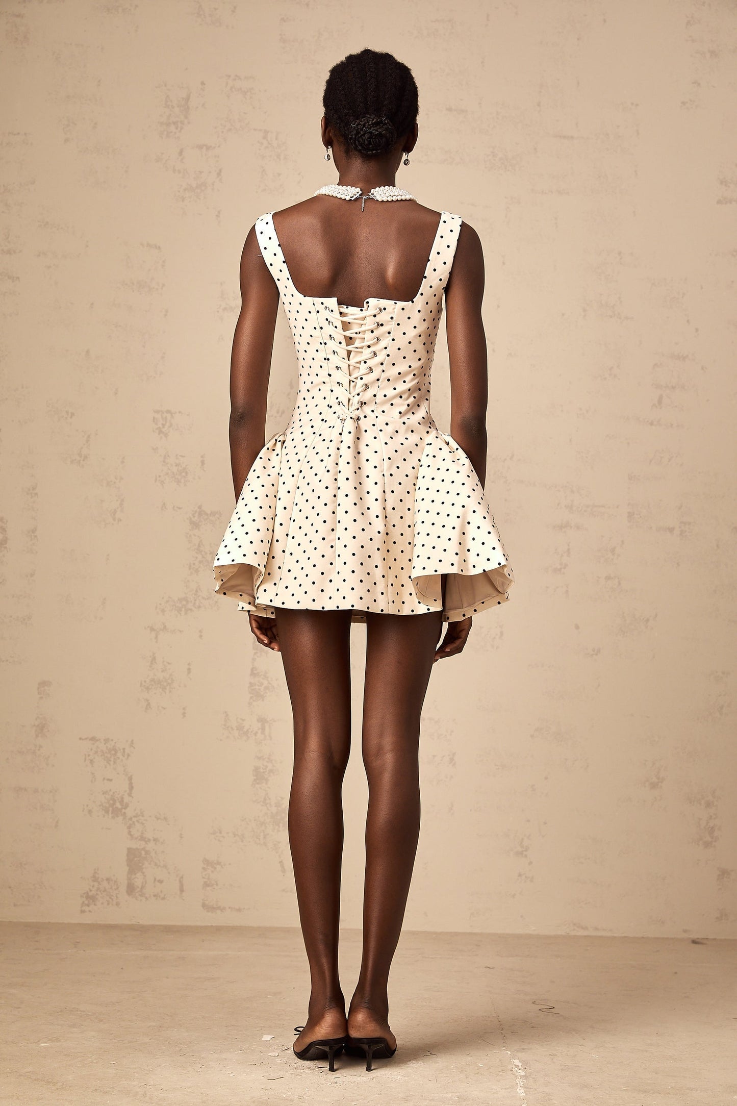 Woman wearing short polka dot dress with puff sleeves in neutral tones