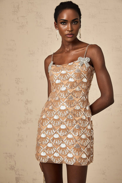 Woman wearing short sparkly gold dress with long sleeves and high neckline