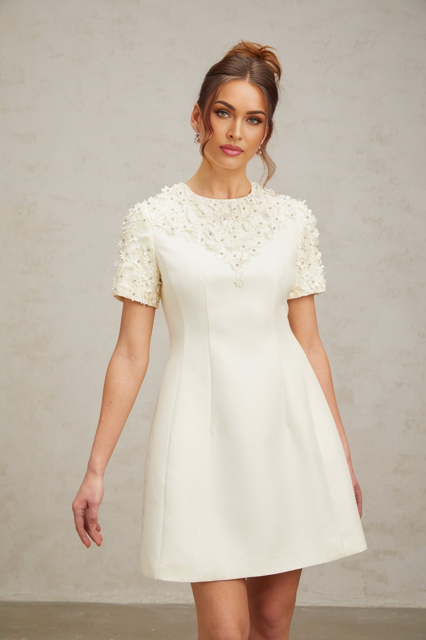 Woman wearing short white dress with colorful floral applique details and puff sleeves