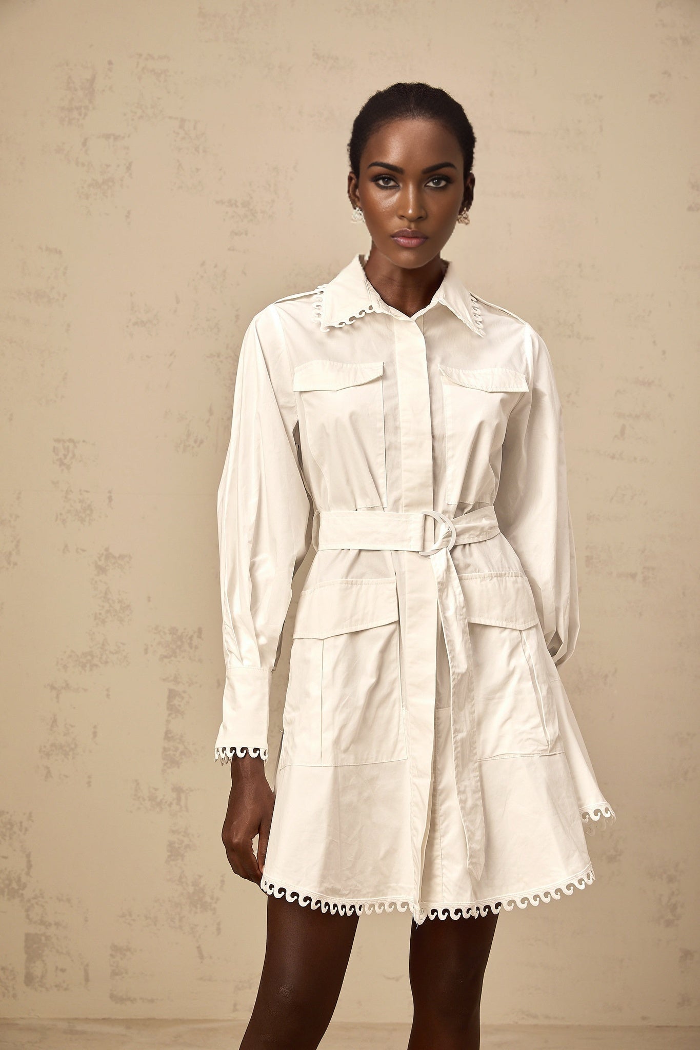 Woman wearing short white shirt dress with belt at waist and buttonup front
