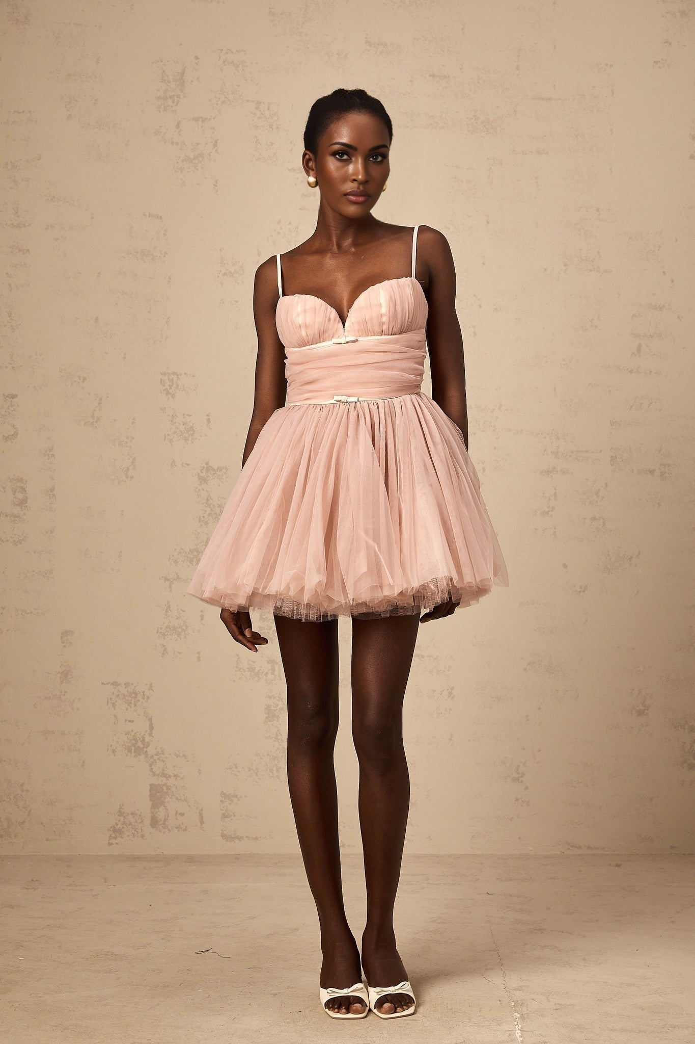 Woman wearing short white sleeveless dress with pleated tulle skirt