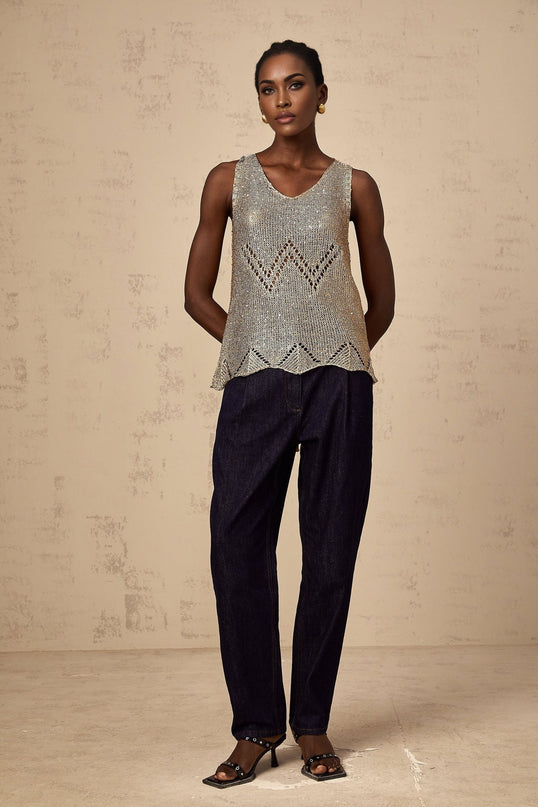 Woman wearing sleeveless gold sequined crochet vest top with intricate pattern