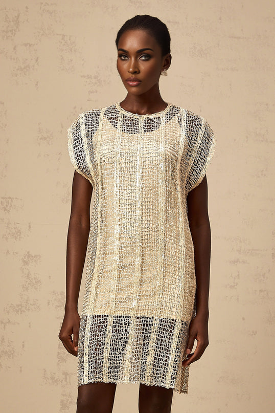 Woman wearing sleeveless gold sequined mini dress with cut out details on sides