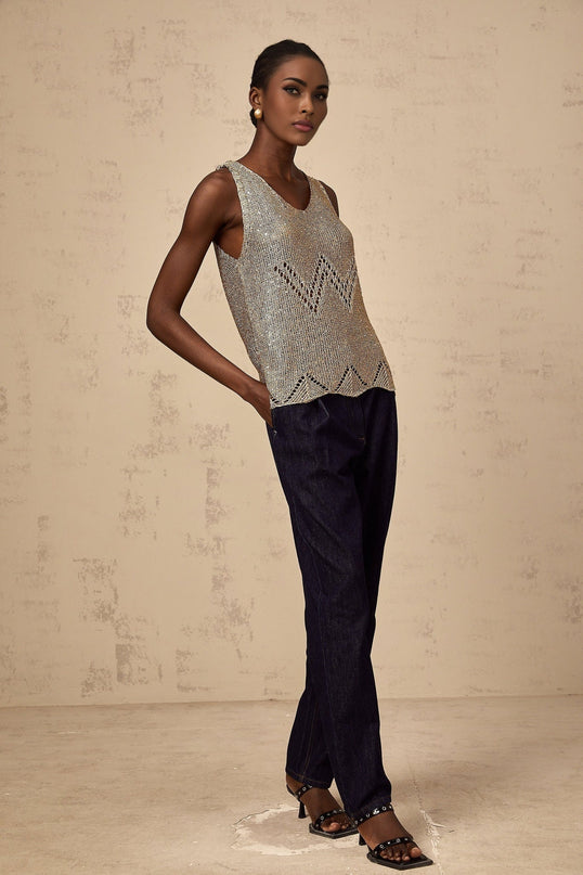 Woman wearing sleeveless gold vest top with sequin embellishments and crochet pattern