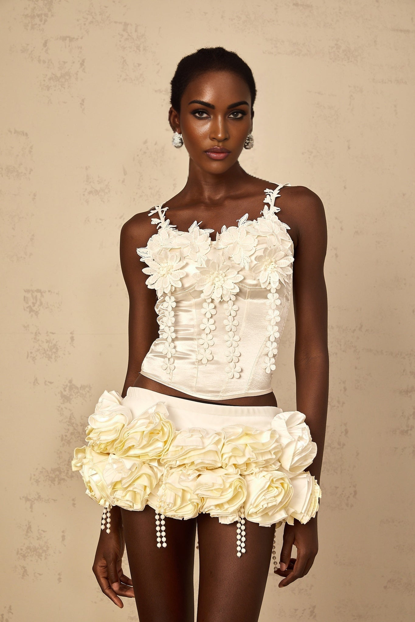 Woman wearing white cropped top with floral embroidery detail and thin straps