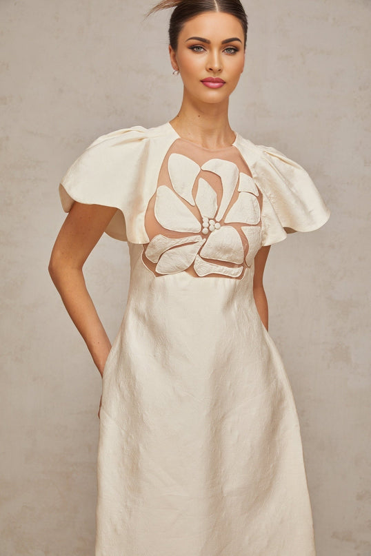 Woman wearing white floral patterned midi dress with jacquard fabric standing in front of neutral background