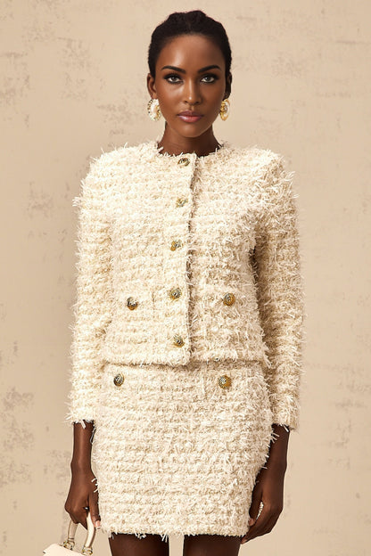 Woman wearing white fluffy knit cardigan and matching skirt set against plain background