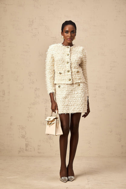 Woman wearing white furry knit cardigan and matching skirt set against neutral background