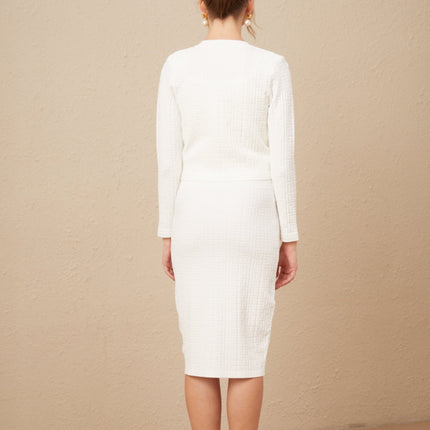 Woman wearing white knit cardigan with allover monogram pattern and button front closure