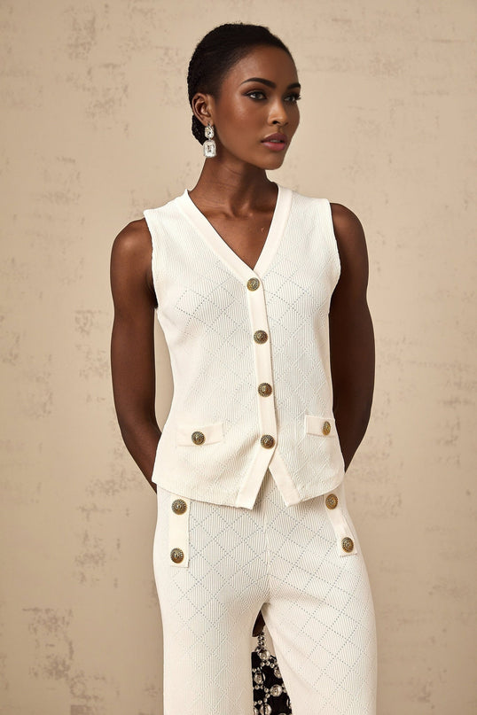 Woman wearing white knitted top and matching trousers lounging comfortably on sofa