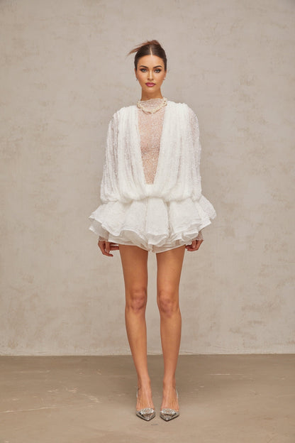 Woman wearing white lace matching set consisting of semi sheer top shorts and dress