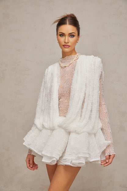 Woman wearing white lace matching set consisting of top shorts and dress Semi sheer fabric with floral lace pattern Elegant summer outfit