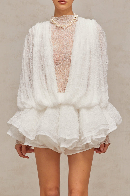 Woman wearing white lace matching set including top shorts and dress semi sheer fabric floral lace pattern delicate feminine design