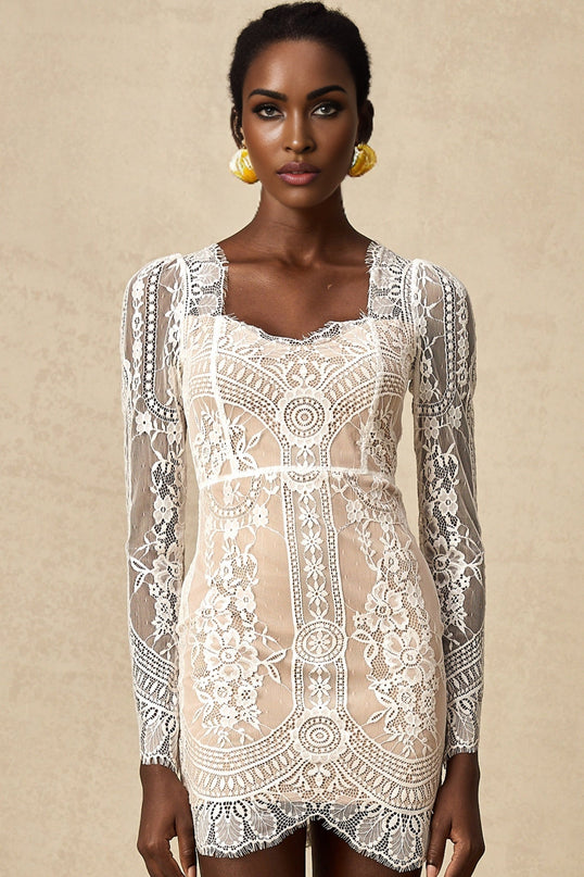 Woman wearing white lace mini dress with scalloped hem and short sleeves standing against plain background