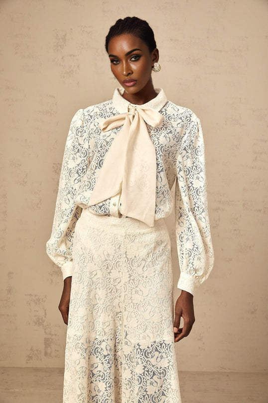 Woman wearing white lace shirt and matching trousers set featuring guipure lace details