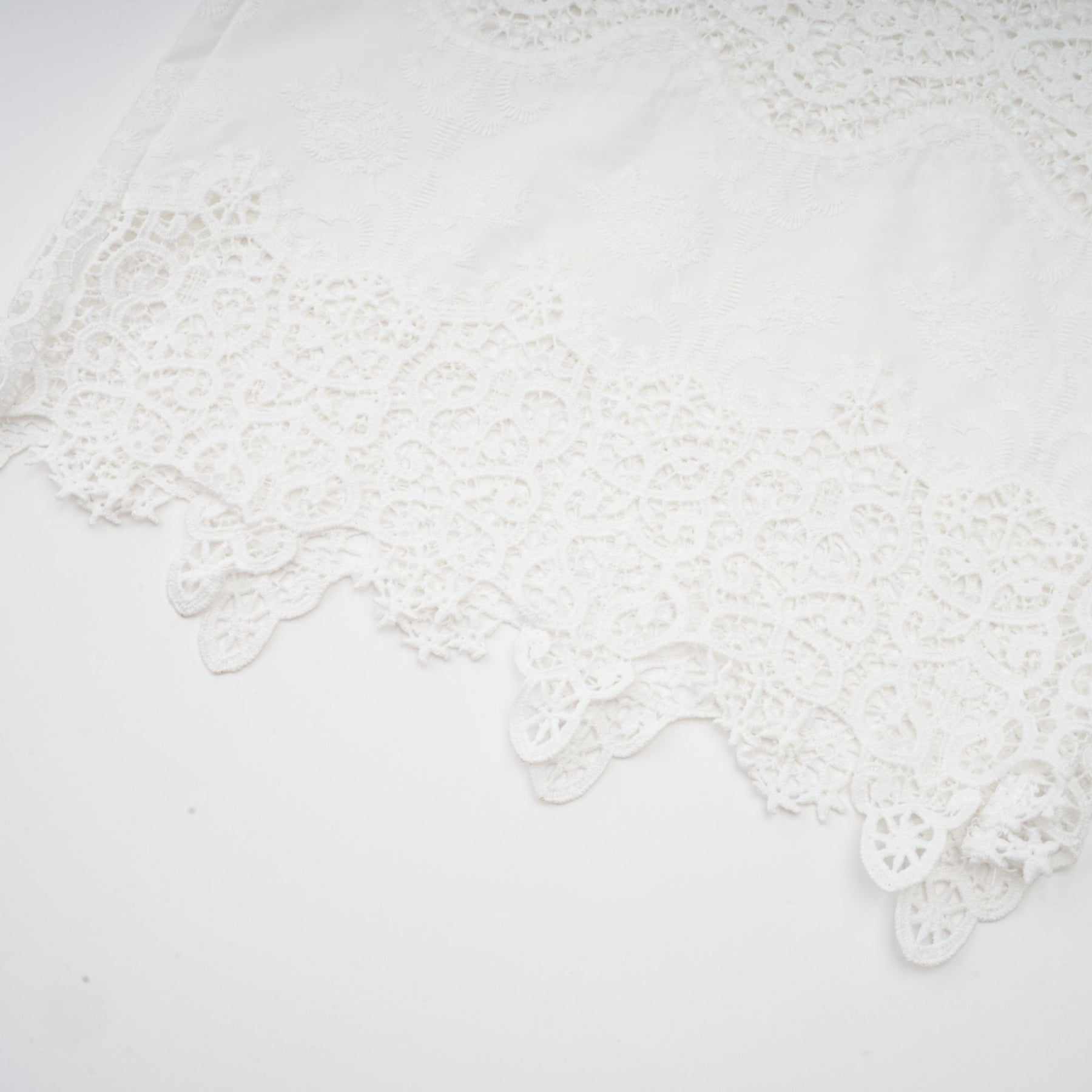 Woman wearing white lace trim cropped top and matching trousers with cutout details Raphaelle matching set