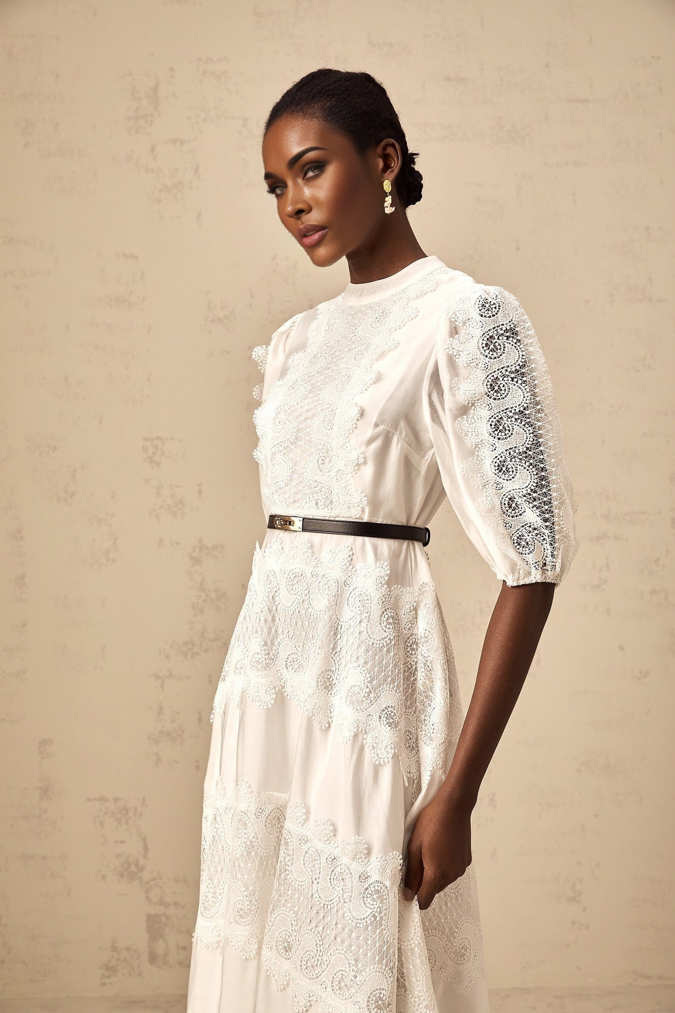 Woman wearing white midi dress with lace trim panels and belt at waist
