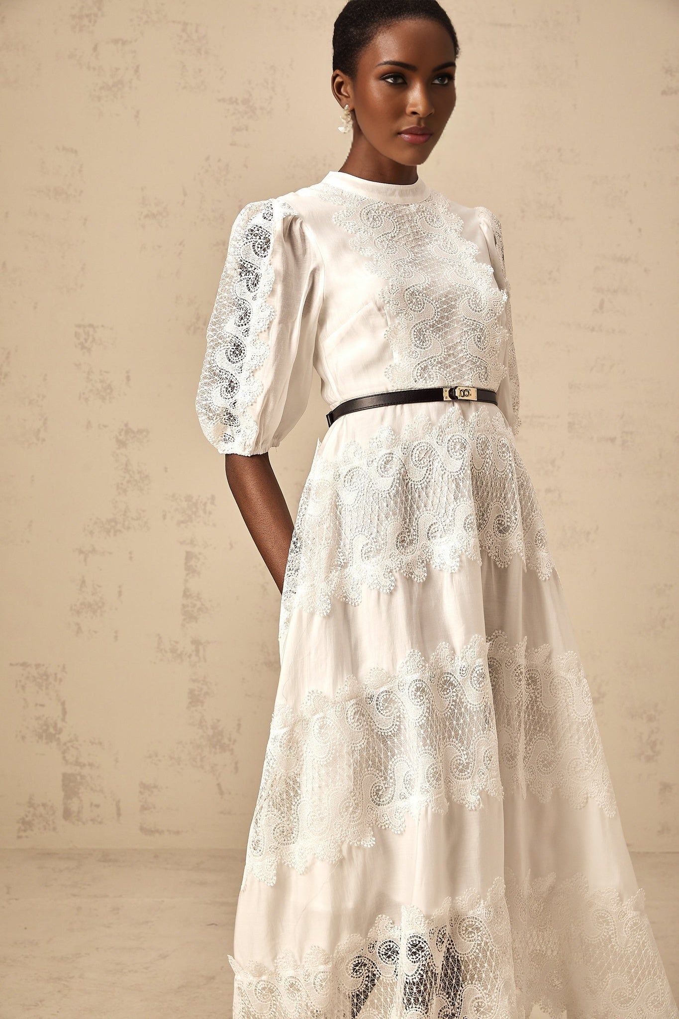 Woman wearing white midi dress with lace trim panels and belt at waist