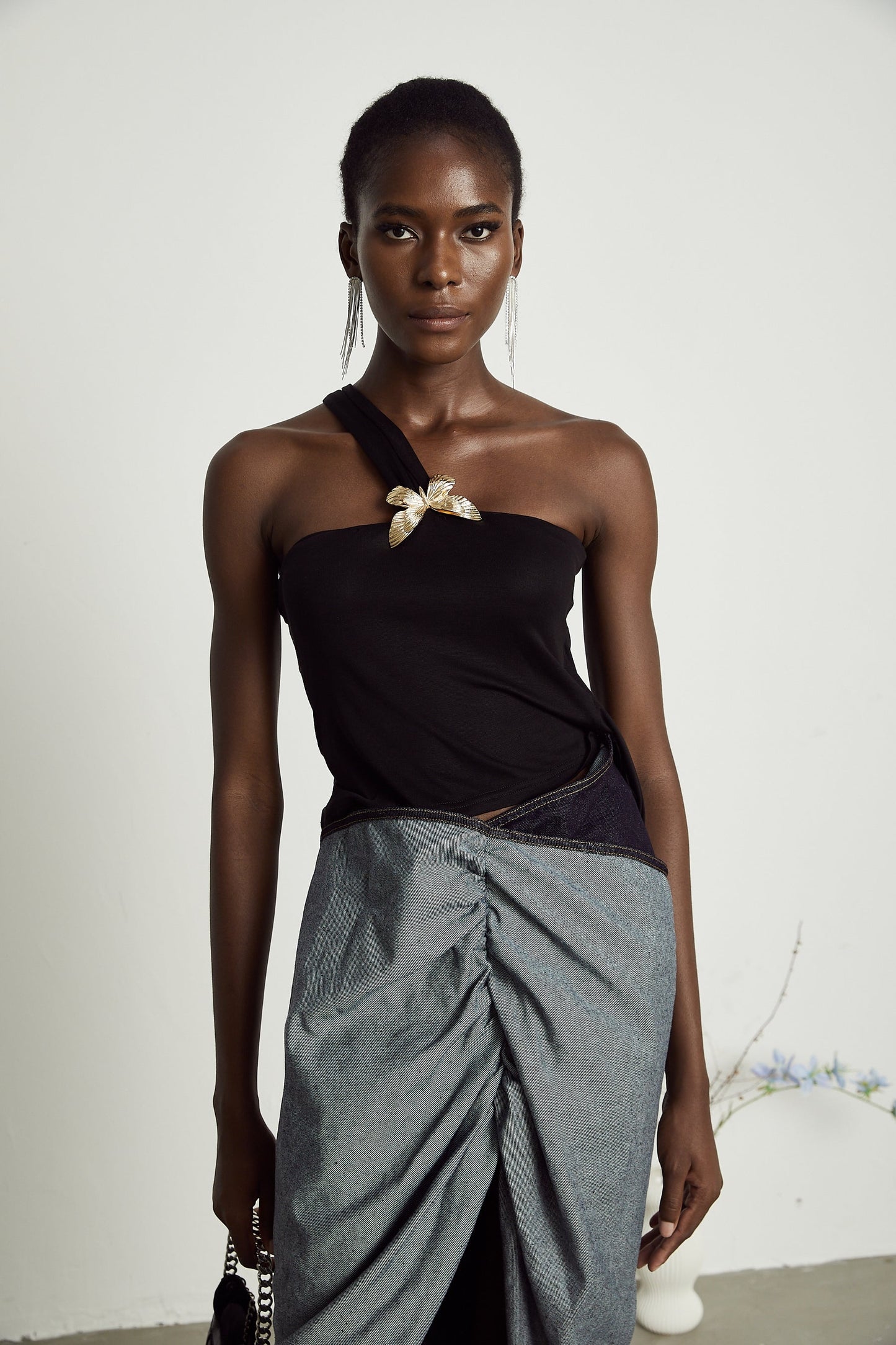 Woman wearing white one shoulder sleeveless top with ruffled neckline