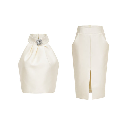 Woman wearing white sleeveless top and matching white skirt standing against plain background