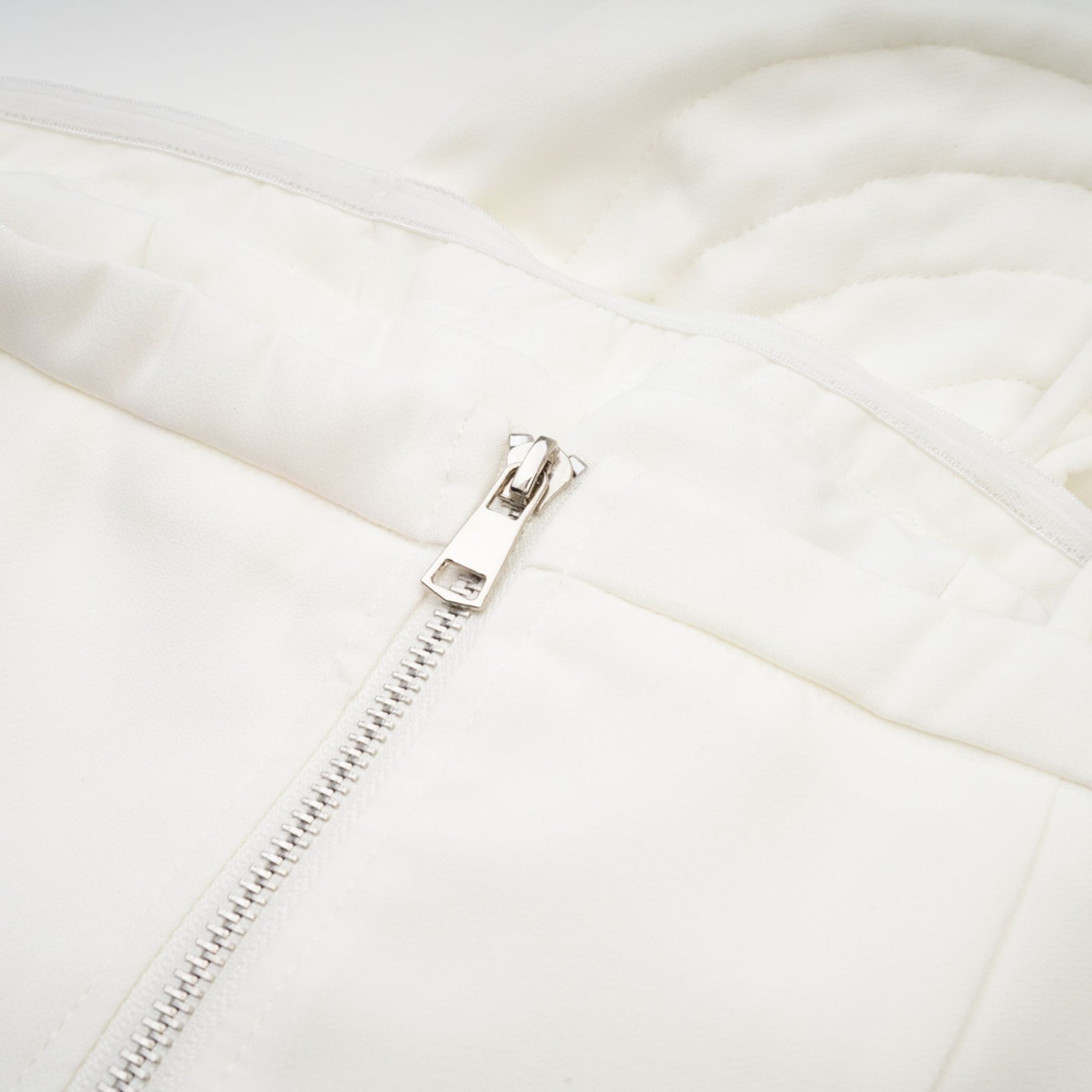 Woman wearing white sleeveless top with delicate floral applique details on the bodice