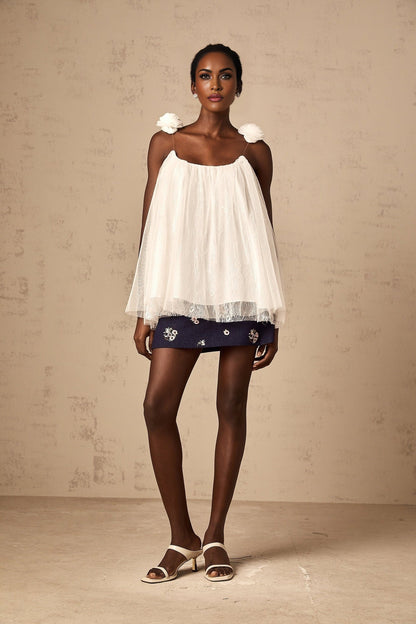 Woman wearing white sleeveless top with floral mesh applique detail