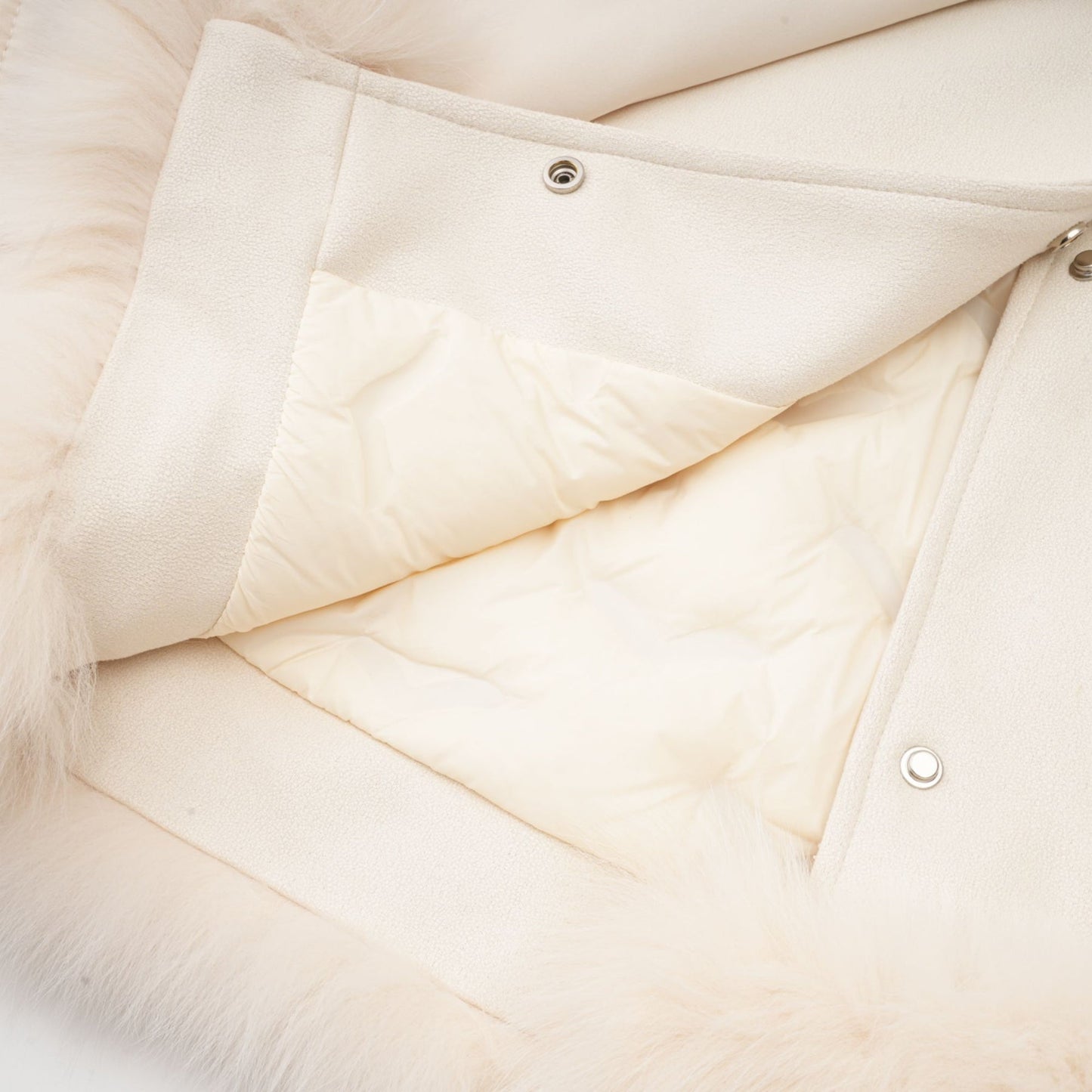 Woman wearing white suede short coat with fur trim and padded design standing against plain background