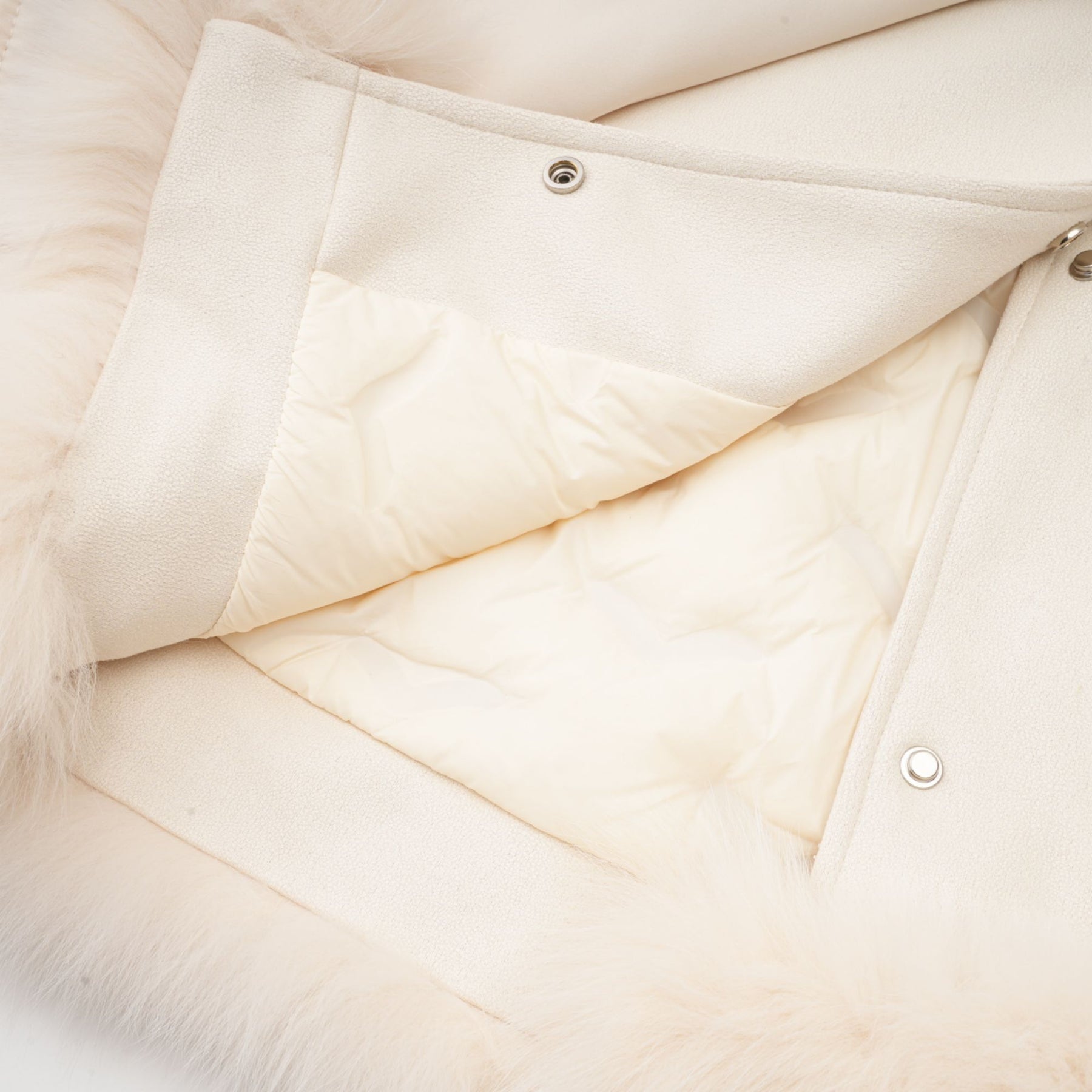 Woman wearing white suede short coat with fur trim and padded design standing against plain background