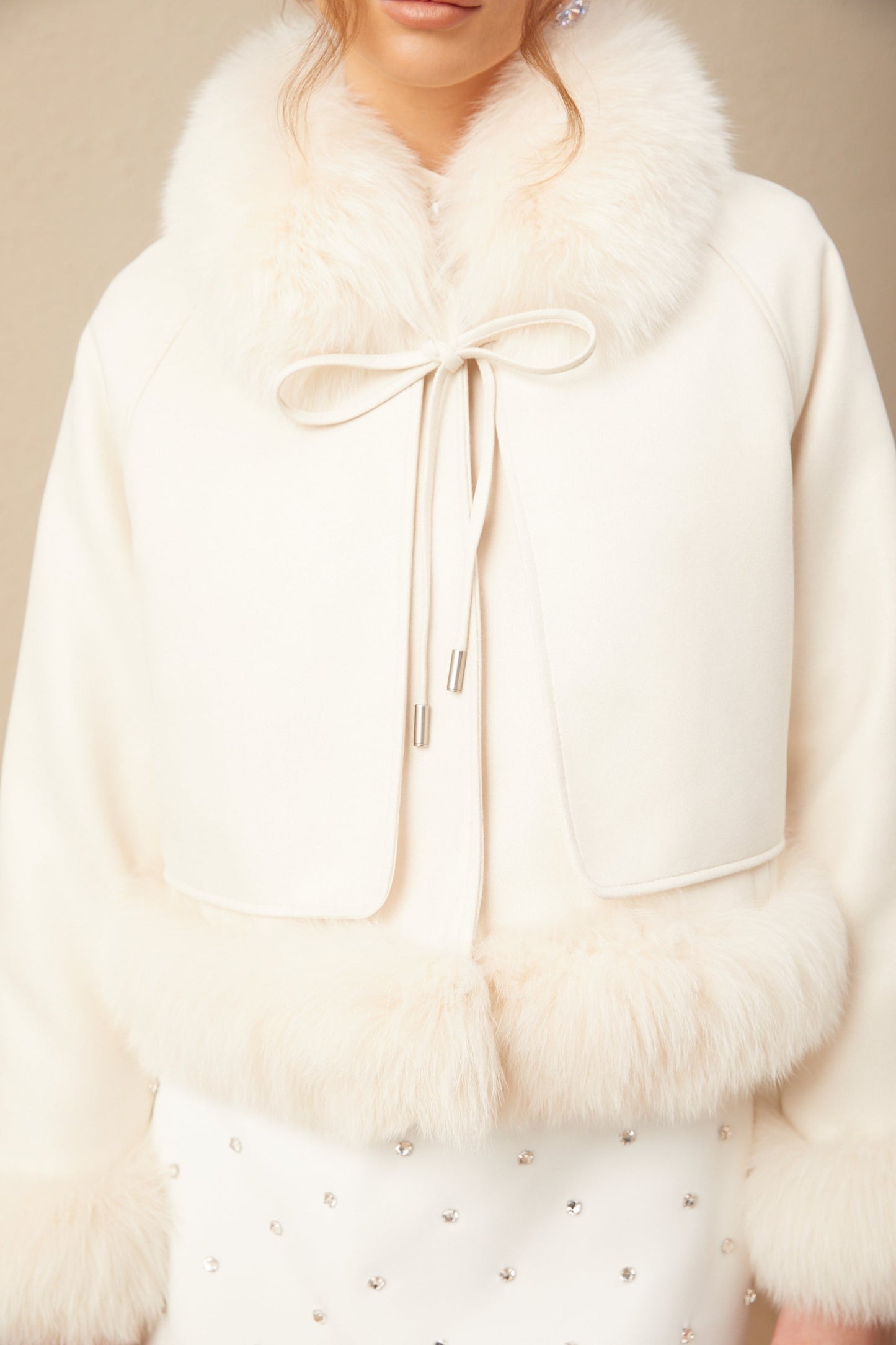 Woman wearing white suede short coat with fur trim and padded design