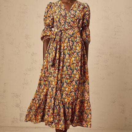 Woman wearing yellow midi dress with Vneck and floral print pattern standing in relaxed pose