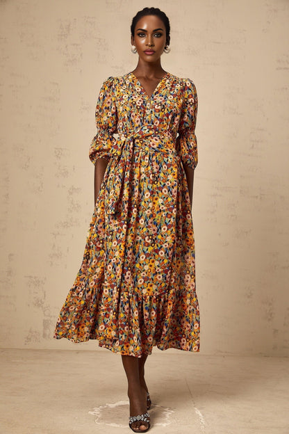 Woman wearing yellow midi dress with Vneck and floral print pattern standing in relaxed pose