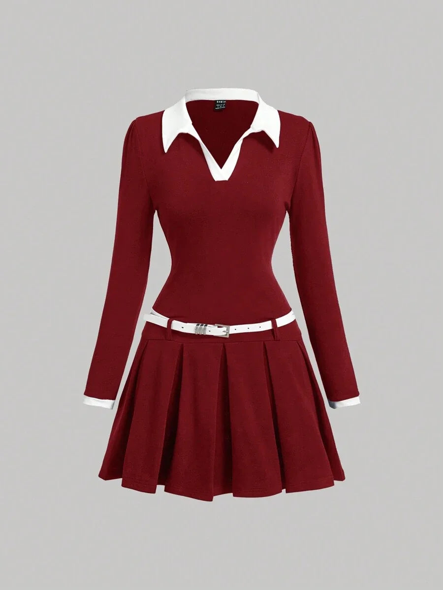 Burgundy contrast collar dress with a pleated skirt, fitted waist, and belt, featuring a polished preppy style with long sleeves and white accents