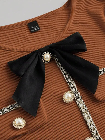 Brown knitted mini dress with pearl buttons, satin bow, and decorative pockets, featuring a tailored fit and ribbed texture for an elegant yet cozy look