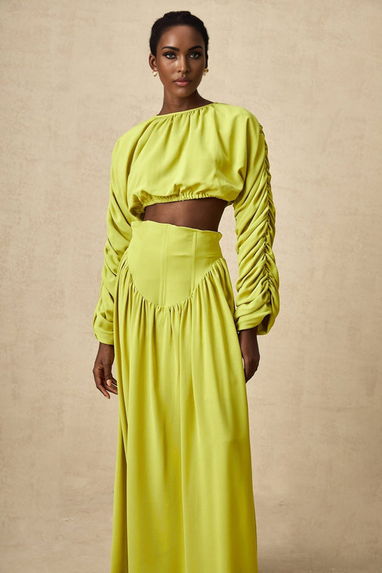 Young girl wearing a green smocked top and matching skirt set named Emilie