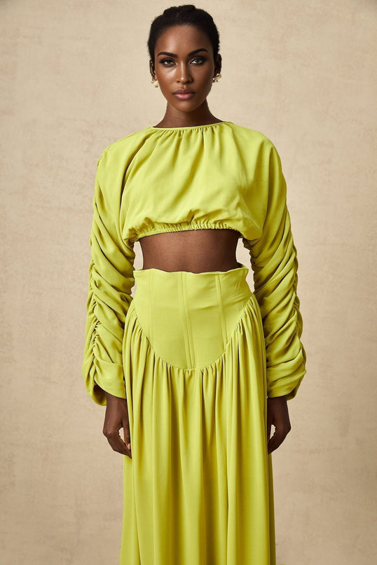 Young girl wearing a green smocked top and matching skirt set named Emilie